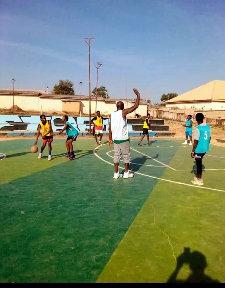 Young basketball players receiving coaching on an outdoor court